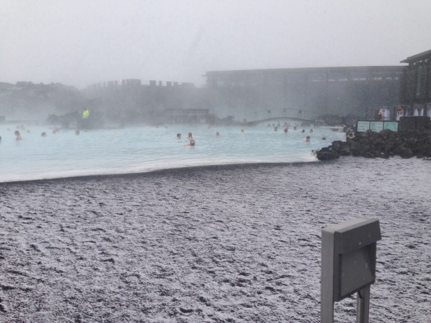Snow blankets the ground around the thermal pool.